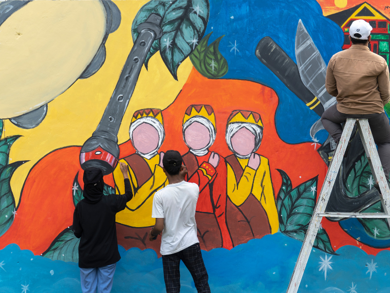 Street artists painting a wall mural